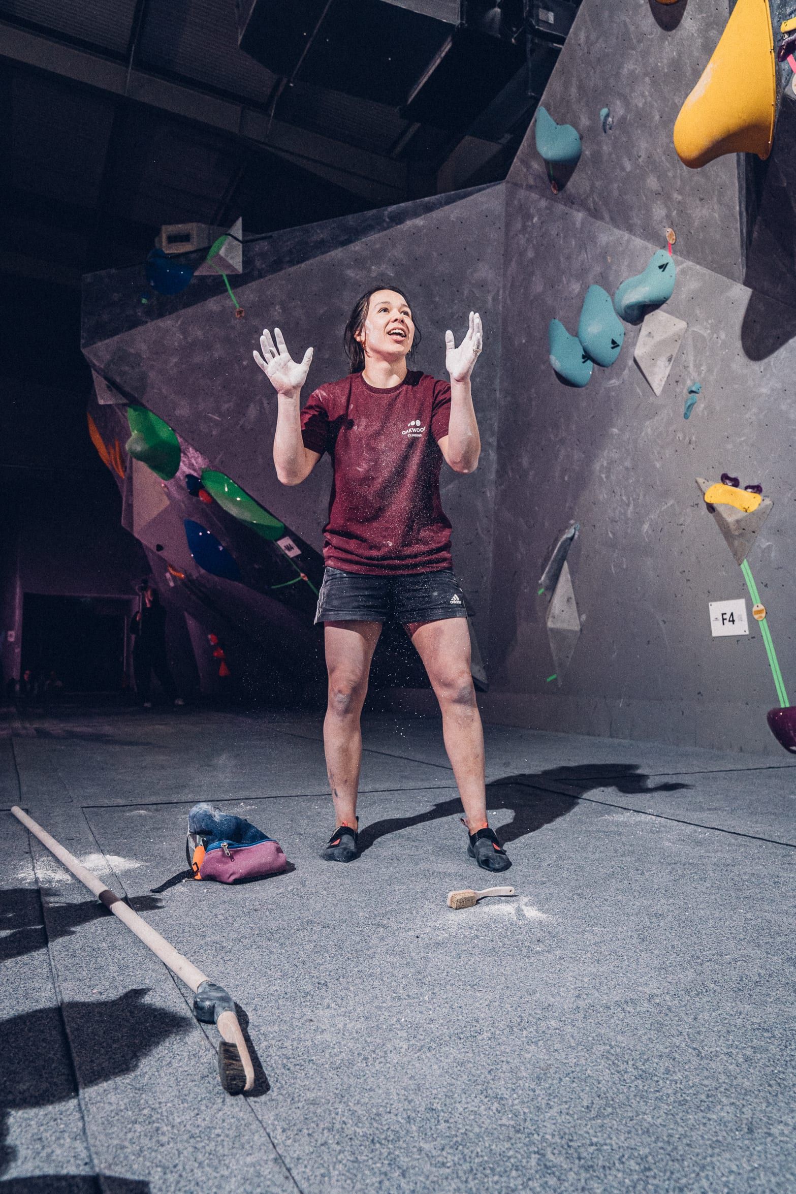Kitty standing in a bouldering gym with chalky hands raised